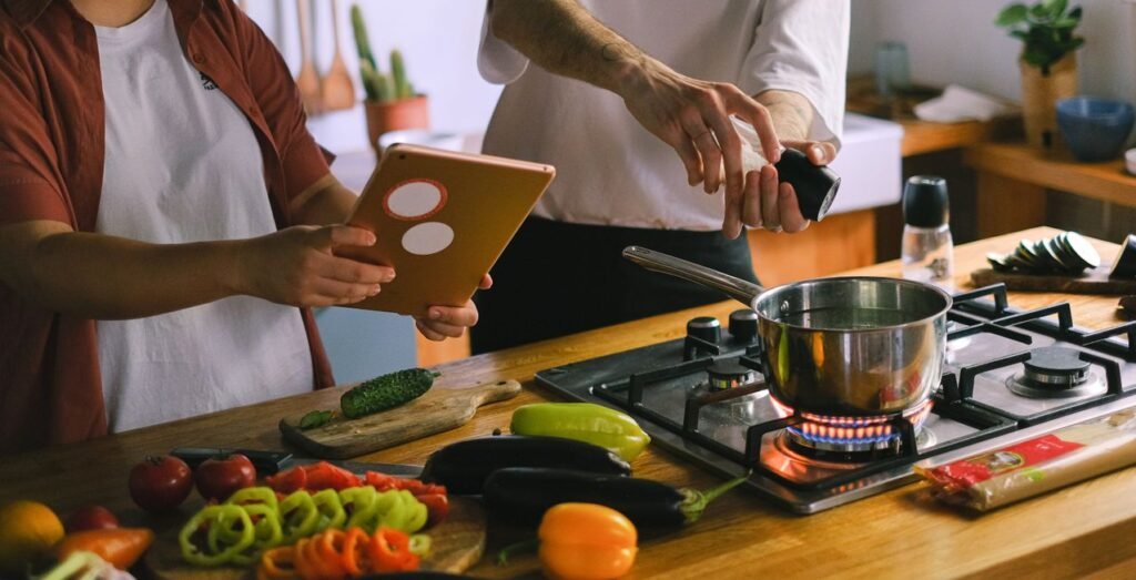 A happy couple using a tablet while preparing a meal in a stylish kitchen.